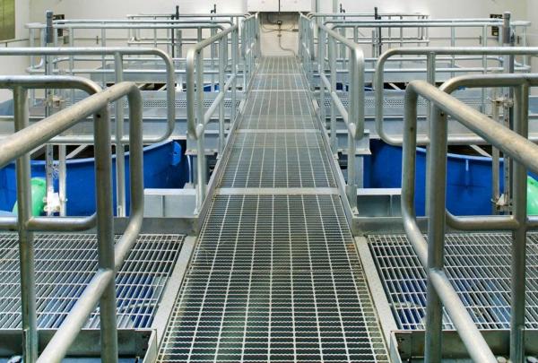 Aluminum grating walkways above six large blue tanks at the 印度头澳门足彩app.